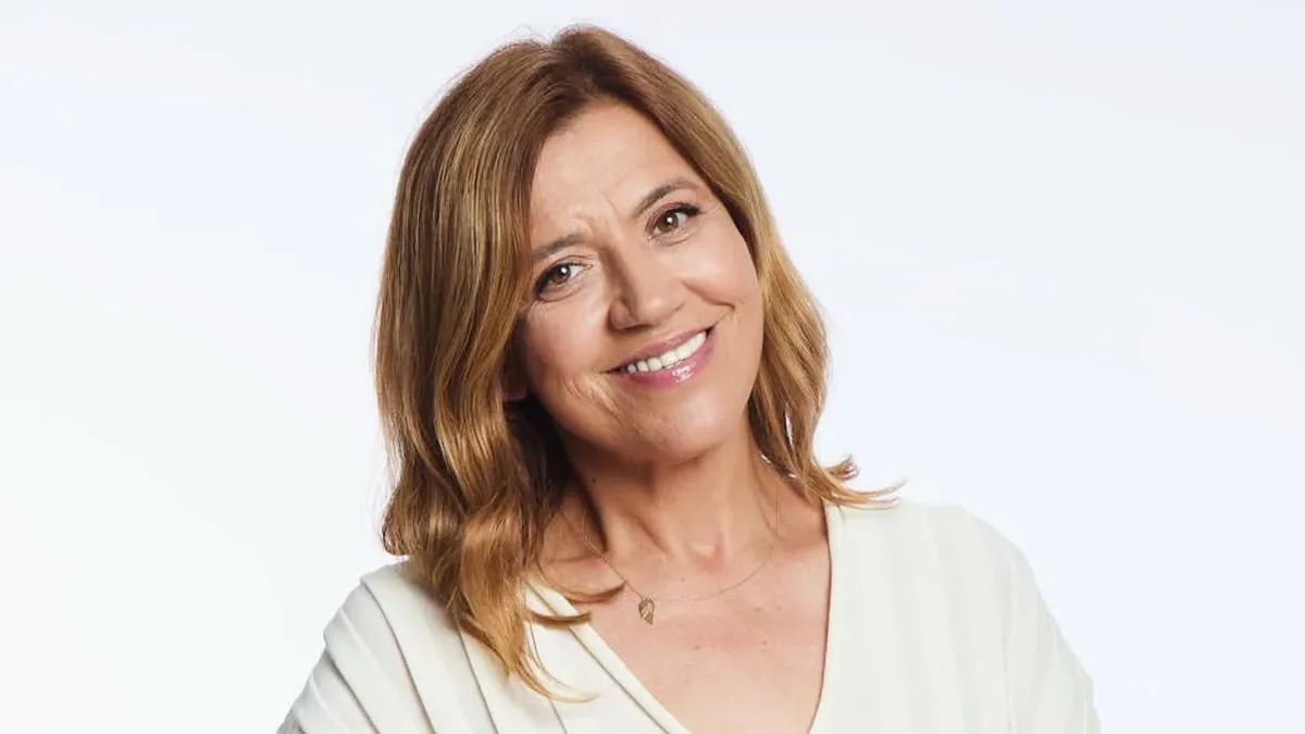 Mirela Retegan zâmbește spre cameră, într-o ținută albă, pe fundal alb.