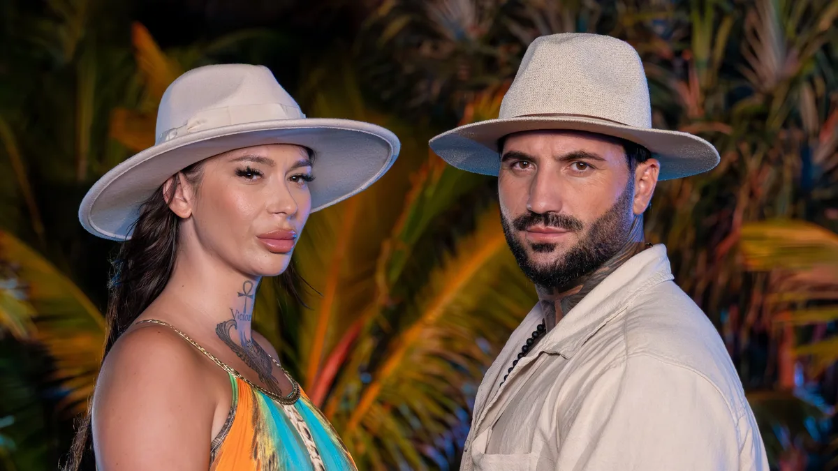 Armina Andrei și Marcel Andrei poartă pălării deschise la culoare și se țin de mâini, în fața vegetației tropicale.