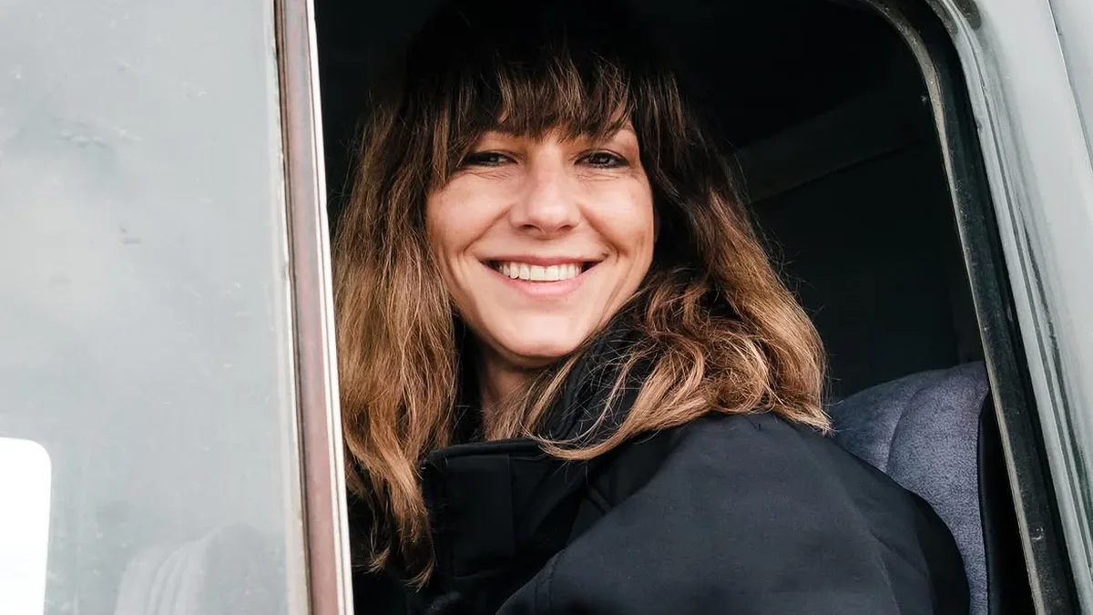 Connie Preda zâmbește prin geamul lateral deschis al unui vehicul verde.